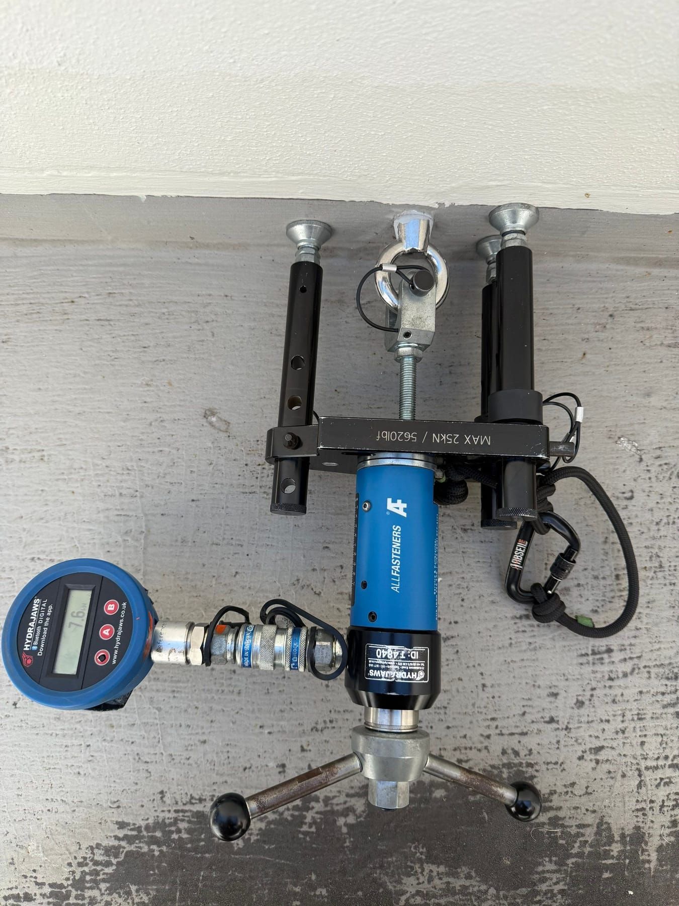 Digital hydraulic pull-test gauge and rig attached to a wall for anchor testing